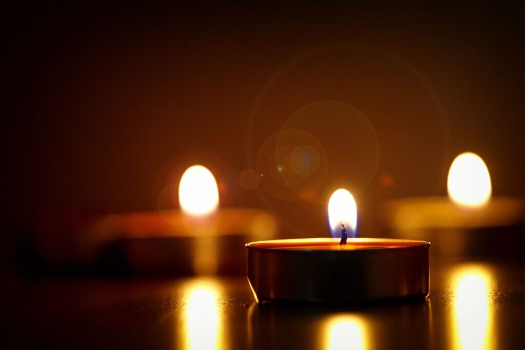 Close-up of illuminated tealight candles casting a warm and reflective glow.