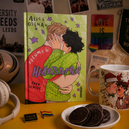 Volume 6 da série Heartstopper sobre a mesa com vários elementos que remetem ao universo.